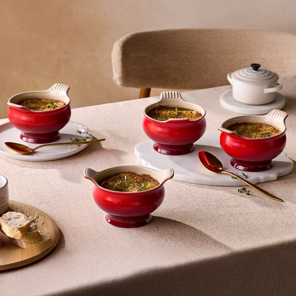 Four red ceramic soup bowls with soup on table