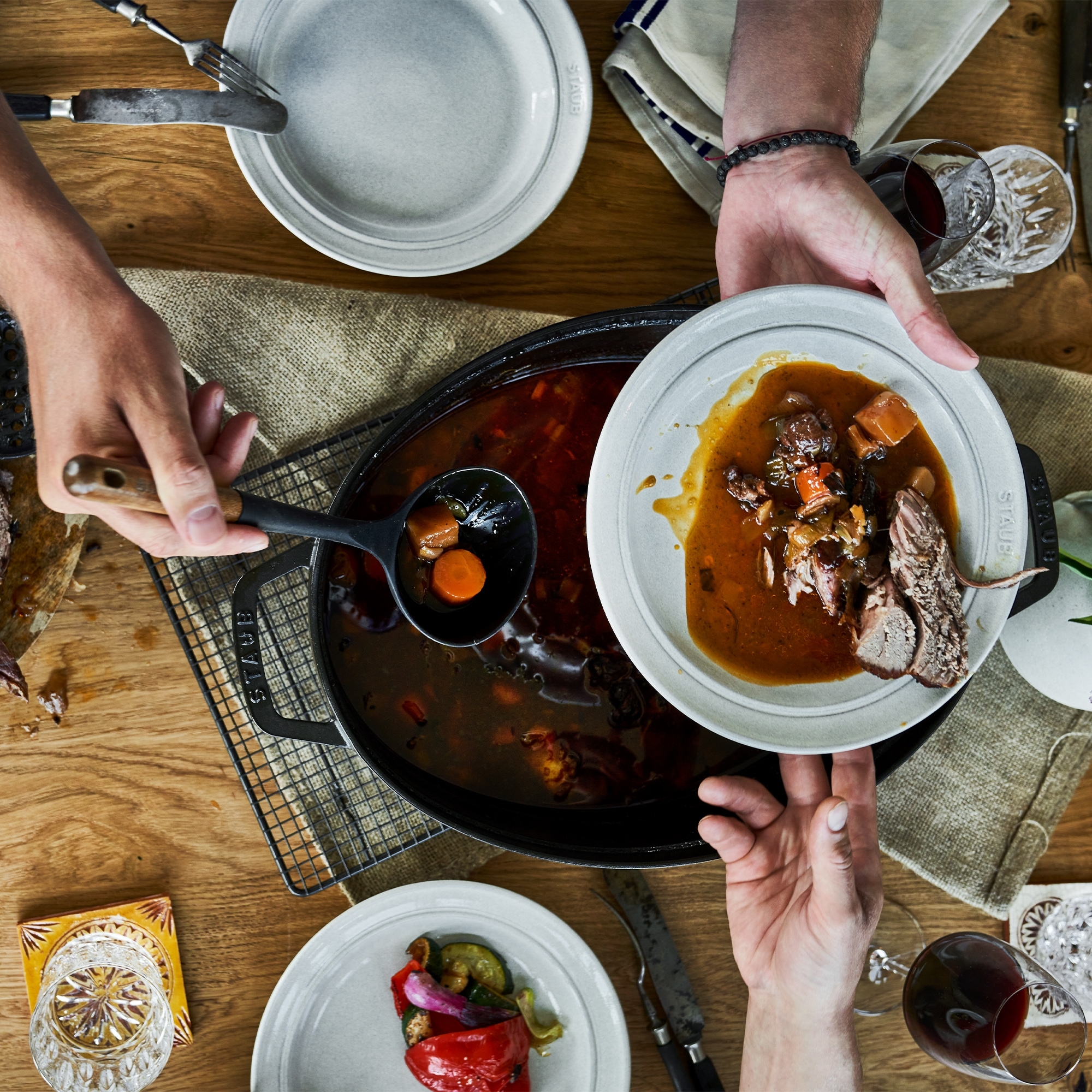 Person serving stew with meat and vegetables on grey plate